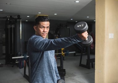 Ciddi ve atletik bir adam halterli halterleri kaldırır. Anterior deltoid omuz egzersizi ve spor salonunda eğitim..