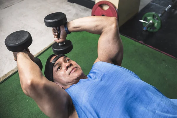 筋肉質でバフアジアの男は嘘のダンベルトリップ拡張のセットを行います ジムでのトリップと腕の練習 — ストック写真