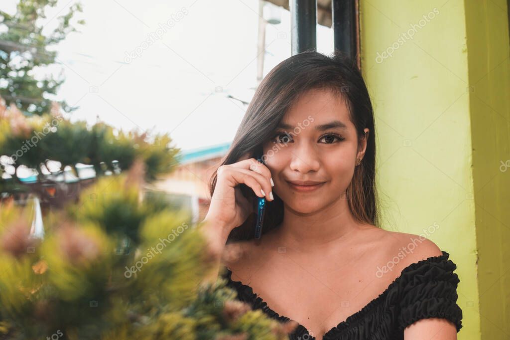 A pretty southeast asian lady with a fashionable crop top and talking on the phone