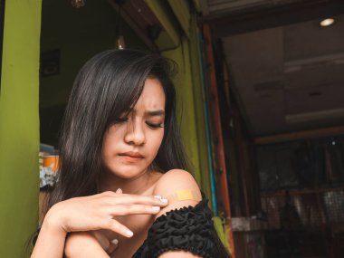 Güzel bir Filipinli kız omzunda yara izi ya da leke bırakabilecek yara bandıyla kaplı küçük bir yara yüzünden rahatsız olur...
