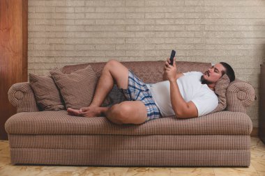 İşsiz ve tembel bir adam bütün gün kanepede yatarken sosyal medyasını ya da interneti karıştırıyor.