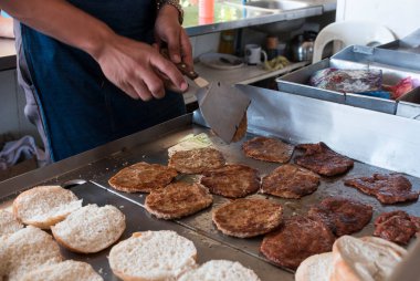 Hamburgerci açık büfede hamburger çevirir..
