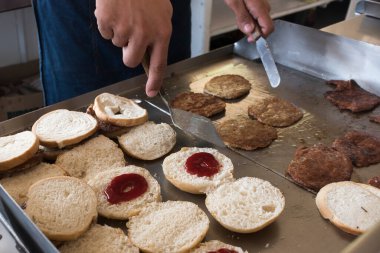 Hamburger köftesi çevirme ve hamburgercide ızgara ekmeğin üstünde ısıtma..