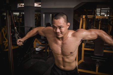 Ciddi ve kararlı bir Filipinli sporcu kablolu yayın yapıyor. Göğüs kaslarını çalıştırıyorum..