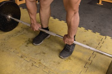 Halter kaldırma işlemini önceden hazırlanmış ya da üstten kavrama yöntemiyle yapmak. Kirli bir kauçuk zeminde. Sıkı spor salonu ayarları.