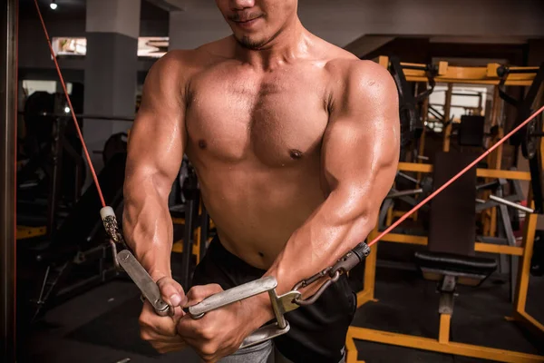 Spor salonunda kablolu yayın yaparken kaslarını sıkan kaslı bir Asyalı..