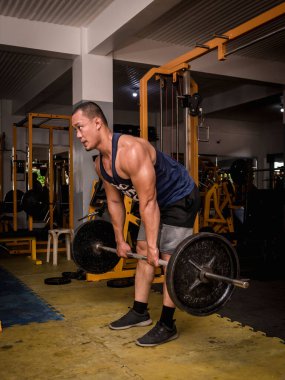 Odaklanmış ve kararlı bir fitness modeli, endüstriyel bir spor salonunda düzenli olarak kaldırma yapıyor..