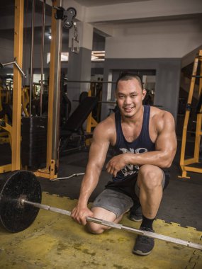 İyi yapılı ve dayanıklı bir adam bir dizi askeri baskı yaptıktan sonra halterle yerde poz verir..