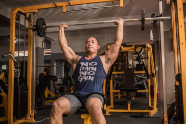 Atletik ve haşin bir Asyalı, Askeri Basın mensubu. Spor salonunda omuz egzersizi..