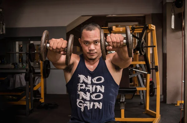 Brawny Muscular Asian Man Does Seated Dumbbell Front Raises Both — Stock Photo, Image