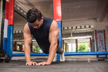 Yakışıklı bir Asyalı, MMA spor salonunda elmas şınav çeker. Vücut ağırlığı jimnastiği ya da HIIT egzersizi. Antrenman göğsü, karın kasları ve trisepsler..