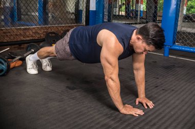 Formda bir Asyalı, MMA spor salonunda sıkı sıkıya şınav çeker. Vücut ağırlığı jimnastiği ya da HIIT egzersizi. Göğüs ve kol kasları çalışıyor..