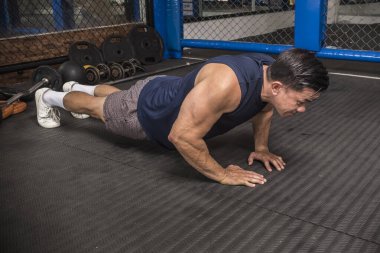 Formda bir Asyalı, MMA spor salonunda sıkı sıkıya şınav çeker. Vücut ağırlığı jimnastiği ya da HIIT egzersizi. Göğüs ve kol kasları çalışıyor..