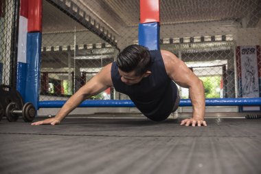Yakışıklı Asyalı bir adam okçu olarak spor salonunda şınav çekiyor. Vücut ağırlığı omuz egzersizi ya da HIIT egzersizi.