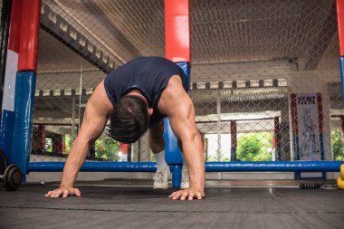 Yakışıklı bir Asyalı MMA spor salonunda şınav çeker. Vücut ağırlığı omuz jimnastiği veya HIIT egzersizi.