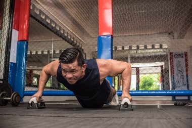 Formda bir Asyalı, MMA spor salonunda barfiks çekerek barfiks çeker. Vücut ağırlığı jimnastiği ya da HIIT egzersizi. Çalışma sandığı, omuzlar, çekirdek ve trisepsler..