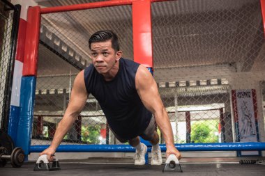 Formda bir Asyalı, MMA spor salonunda barfiks çekerek barfiks çeker. Vücut ağırlığı jimnastiği ya da HIIT egzersizi. Çalışma sandığı, omuzlar, çekirdek ve trisepsler..