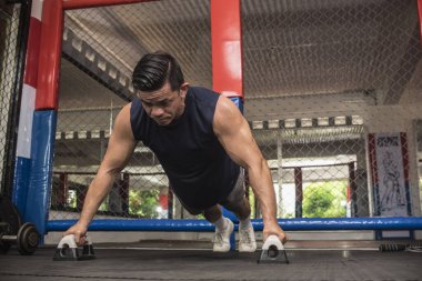 Formda bir Asyalı, MMA spor salonunda barfiks çekerek barfiks çeker. Vücut ağırlığı jimnastiği ya da HIIT egzersizi. Çalışma sandığı, omuzlar, çekirdek ve trisepsler..