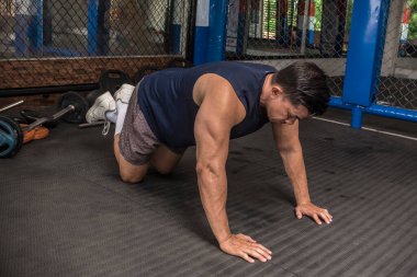 Formda bir Asyalı lastik kaplı zeminde yarım şınav çekmeye hazırlanıyor. MMA spor salonunda HIIT ya da jimnastik egzersizleri.