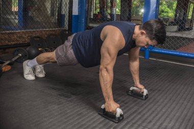 Atletik bir adam kauçuklu zeminde şınav çeker. MMA spor salonunda HIIT ya da jimnastik.