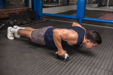 Atletik bir adam kauçuklu zeminde şınav çeker. MMA spor salonunda HIIT ya da jimnastik.