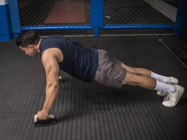 Atletik bir adam kauçuklu zeminde şınav çeker. MMA spor salonunda HIIT ya da jimnastik.