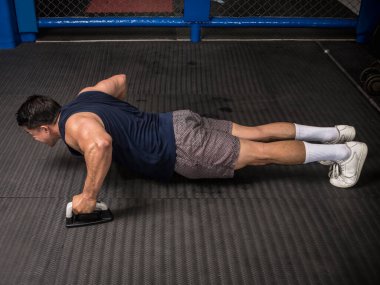 Atletik bir adam kauçuklu zeminde şınav çeker. MMA spor salonunda HIIT ya da jimnastik.