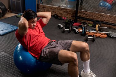 Atletik ve formda bir adam dengeli bir topta mekik çekebilir ya da mekik çekebilir. Abs ve çekirdek egzersizi.