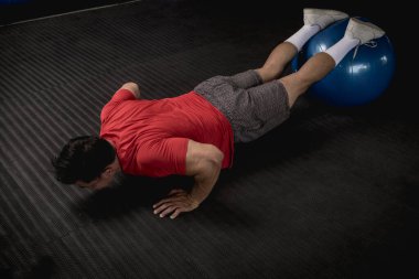 Atletik ve formda Asyalı bir adam dengeli top şınavı yapar. Karın ve çekirdek egzersizi ve egzersiz. Tepeden çekim.