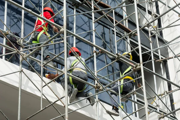 İnşaat işçileri midrise ofis binasının dış cephesinde son işleri yapıyorlar - boyama ve cam döşeme -.