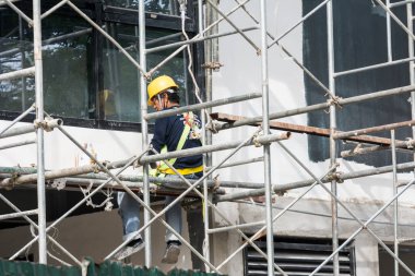 Metro Manila, Filipinler - Nisan 2021: İnşaat iskelesinde çalışan tek inşaat işçisi bir midrise ofis binasının dış cephesinde son işleri yapıyor.