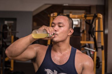 Formda ve dayanıklı bir adam spor salonundaki yoğun antrenman sırasında şişe suyu içer. Sıvı kaybı ve şeker takviyesi..