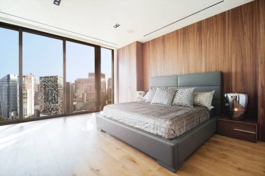 Beyaz tavanlı modern ve lüks bir yatak odası ve BGC ufuk çizgisi manzaralı ahşap parke döşemesi. Metro Manila 'da lüks bir daire ya da otel..