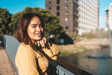 Güzel bir Filipinli kadın köprünün kenarındaki küçük bir nehri ya da gölü geçiyor..