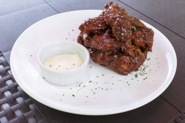 Al Fresko restoranında sarımsaklı mayonez sosuyla servis edilen ekstra sıcak bufalo kanadı. Cayenne, Habanero ya da Hayalet biberli.