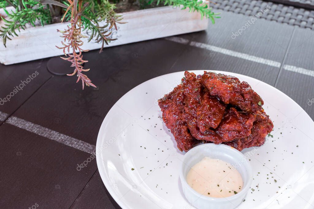 Honey glazed extra hot Buffalo wings served with Garlic mayonnaise dip, at an al fresco restaurant. Spiked with Cayenne, Habanero or Ghost pepper.