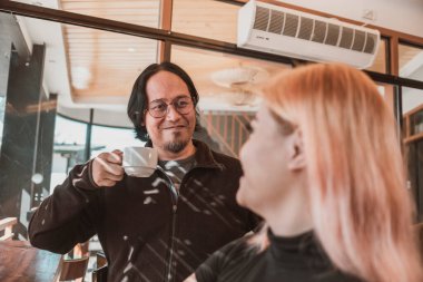 Kahve evi ya da kafe sahnesi yaşlı bir adam daha genç ve çekici bir kadına bir fincan kahve ikram eder..