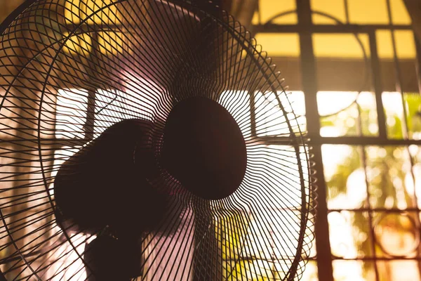 A running electric fan inside a room during a sweltering and hot day. Concept of heat wave or summer weather.