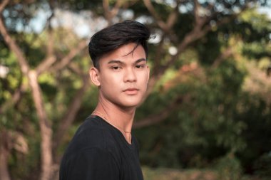 Parktaki yakışıklı Filipinli genç bir adam. Siyah bir tişörtle. Öğleden sonra parkta..