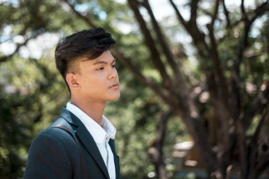 Genç Filipinli bir adam derinlere dalmış, geleceği düşünüyor ya da sorunlu. Boş boş bakıyor ve duygusuz, parkta yürüyor..