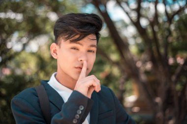 Yakışıklı bir Asyalı sessiz olmak istiyor. İşaret dili işareti, müstehcen cilveli gözler. Gizli ya da cezbedici kavram.