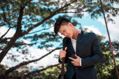 Genç Asyalı bir adam midesi ekşiyor ya da parkta yürürken ya da işe giderken midesi ağrıyor. Genç yetişkinlerde sindirim sorunları.