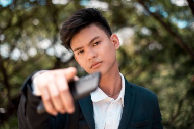 Kibirli genç bir adam kamerayı işaret ediyor. Şımarık ve kendini beğenmiş Asyalı genç.