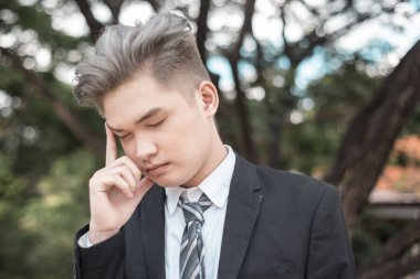 Stresli ve yorgun, külleri sarı saçlı Asyalı bir adam. Çok çalışan Gen Z çalışanı.