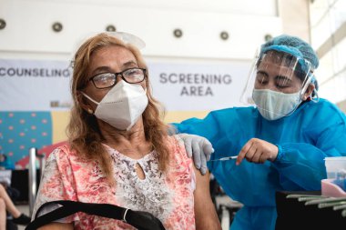 Las Pinas, Metro Manila, Filipinler - Haziran 2021: Yaşlı bir kadın yerel bir alışveriş merkezindeki toplu aşı alanında ilk Pfizer-BioNTech COVID-19 aşısını yaptırdı