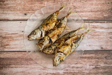 Kızarmış Bigeye dışkısı, Matang Baka olarak bilinir. Ahşap bir masada cam bir tabakta servis edildi..