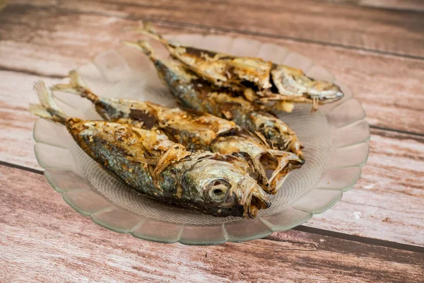 Kızarmış Bigeye dışkısı, Matang Baka olarak bilinir. Ahşap bir masada cam bir tabakta servis edildi..