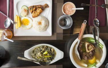 Top view of popular Filipino cuisine served in a restaurant - Bangsilog, Laing, and Beef Bulalo.