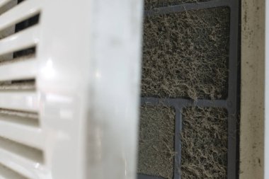 Bölünmüş klima ünitesinin giriş kapağı kirli bir filtreyi ortaya çıkarmak için açıldı..