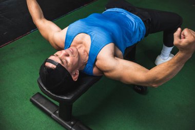 Formda bir adam, yedek kulübesinde uzanırken göğüs kaslarını esneterek ısınır. Göğüs egzersizi için hazırlanıyorum..